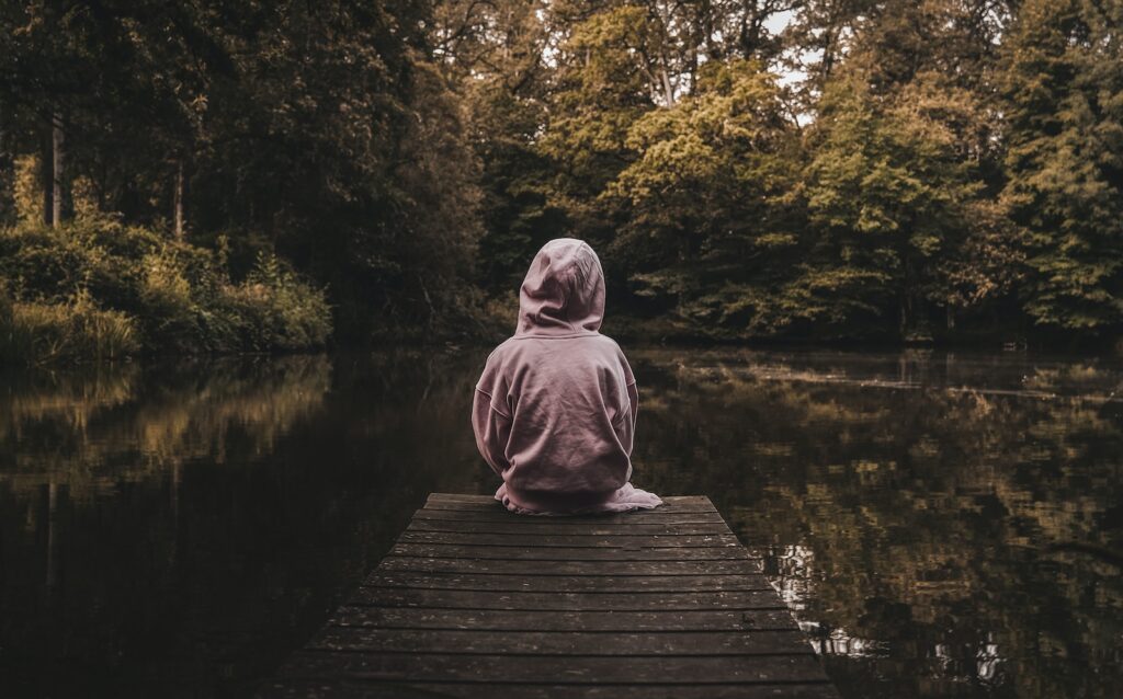 a person sitting on a dock looking at the water