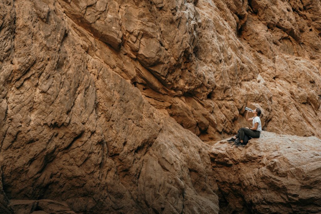 a woman sitting on top of a rock next to a cliff